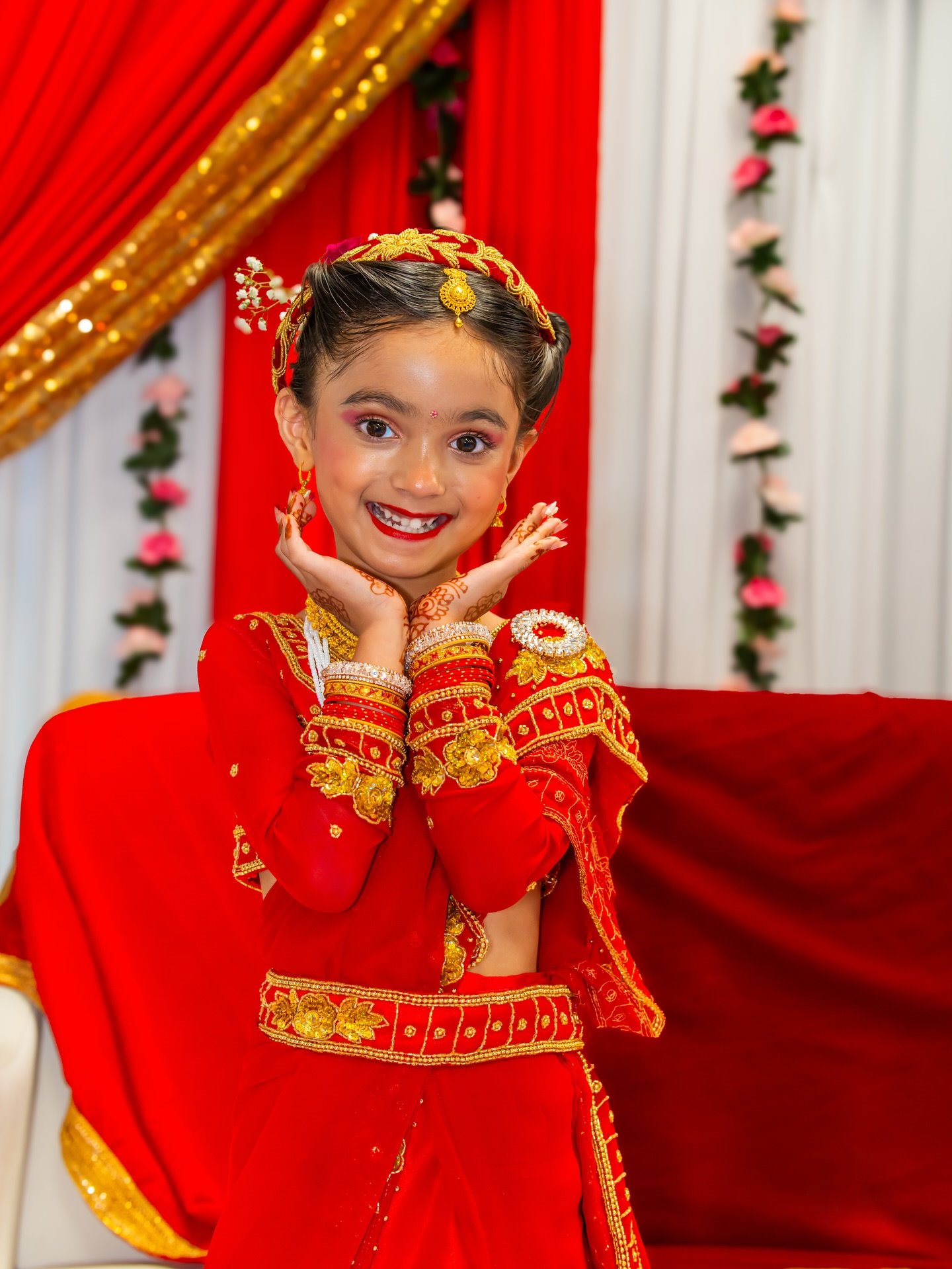A young girl in a red Gunyu Cholo smiling with her hands framing her face