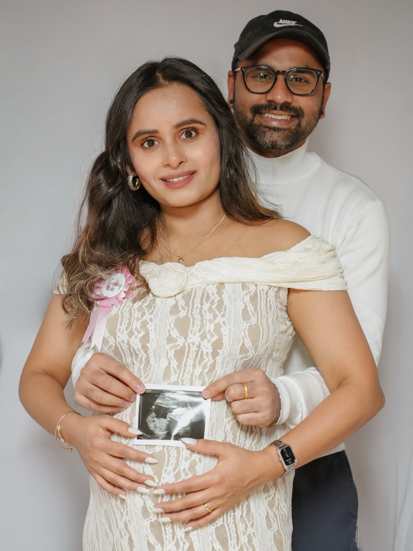 An expectant couple holding an ultrasound picture in front of her bump
